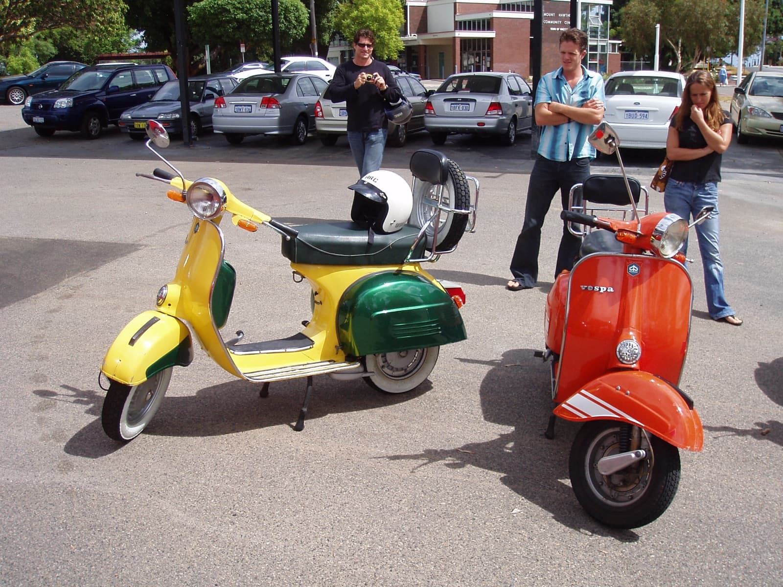 A yellow Vespa and a red Vespa parked next to each other