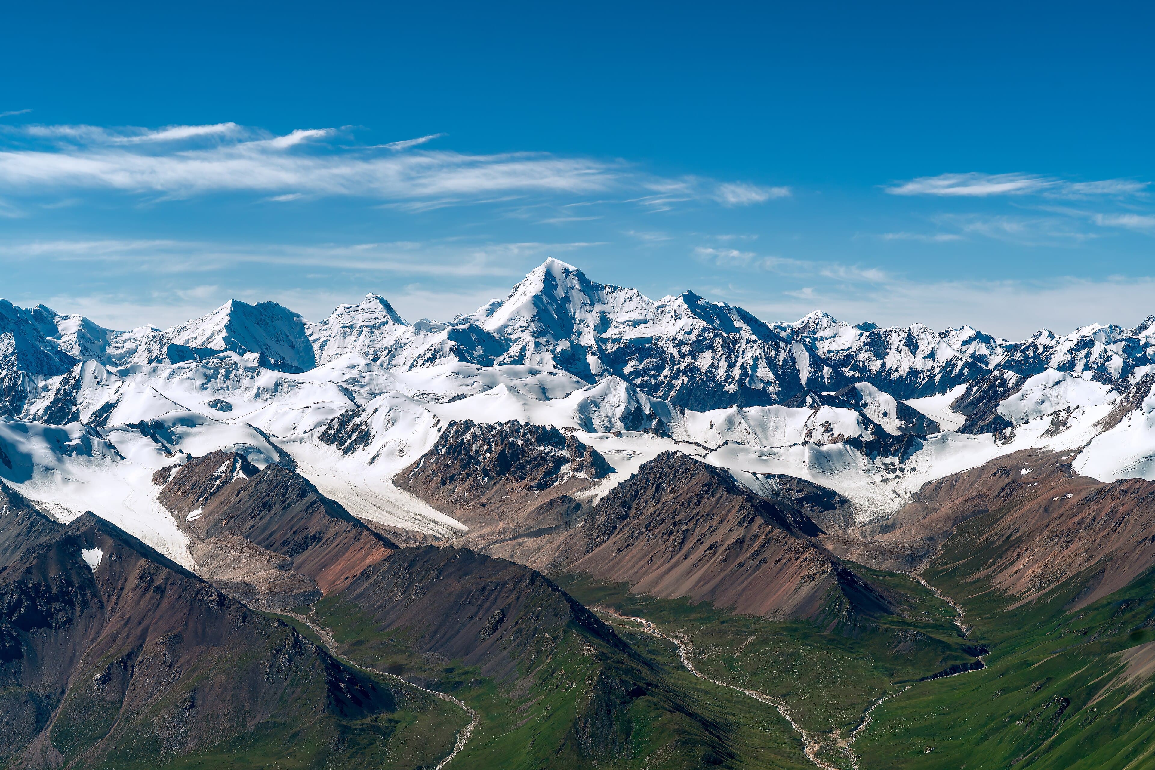 Snow-capped Tien Shan peaks rising above green alpine valleys