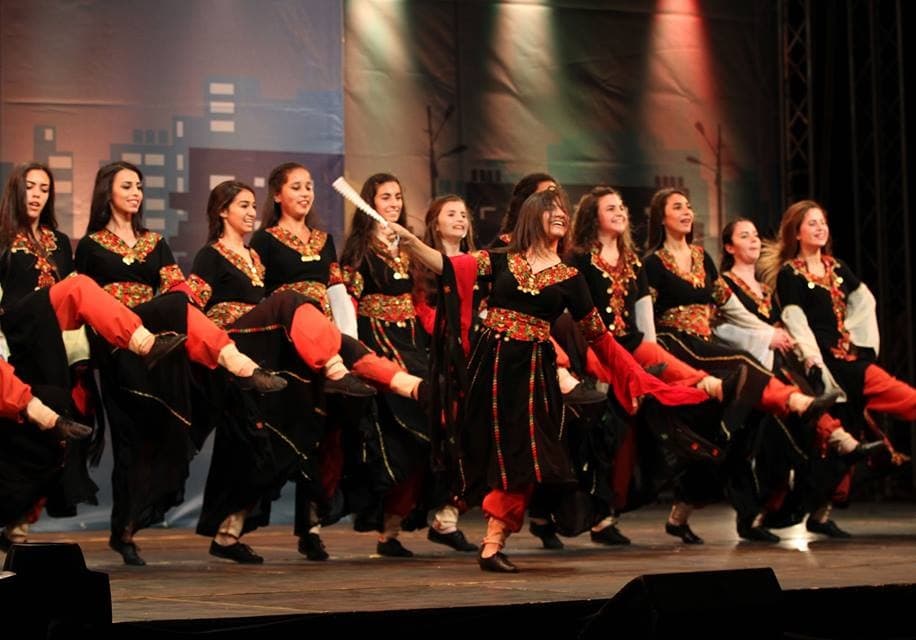 A line of dancers in colourful embroidered costumes performing Dabke at a Jordanian festival
