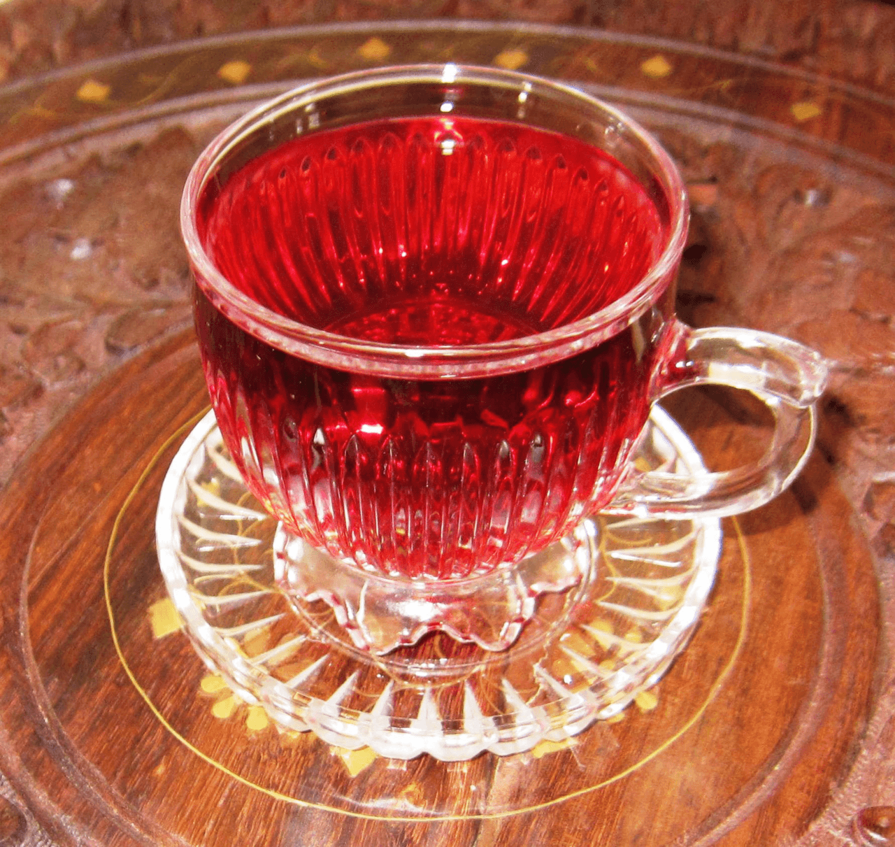 A glass of bright red sorrel drink with ice and a lime slice